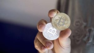a hand holding 2 bitcoin coins